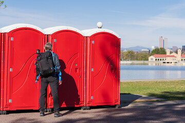 Portable restrooms placed along a lakefront path in the city, with the skyline visible in the background