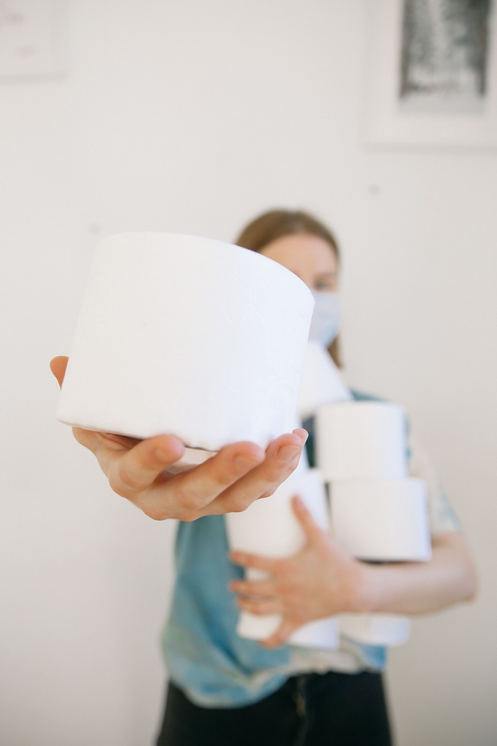 Hand holding a fresh stack of toilet paper rolls