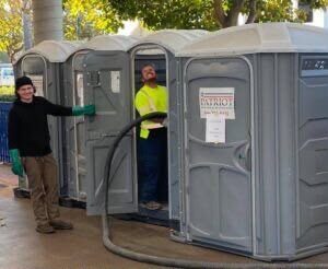Technicians servicing a row of portable restroom units on site