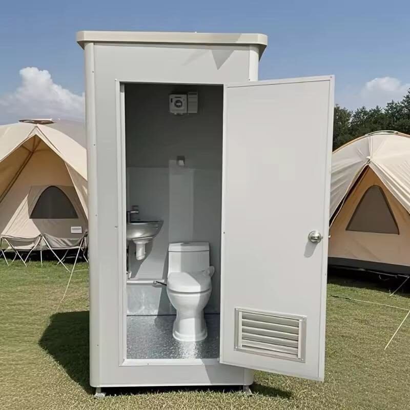 Portable restrooms lit by string lights at an evening event
