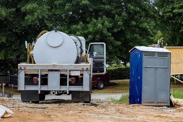 Service technician pumping out and servicing a portable restroom unit