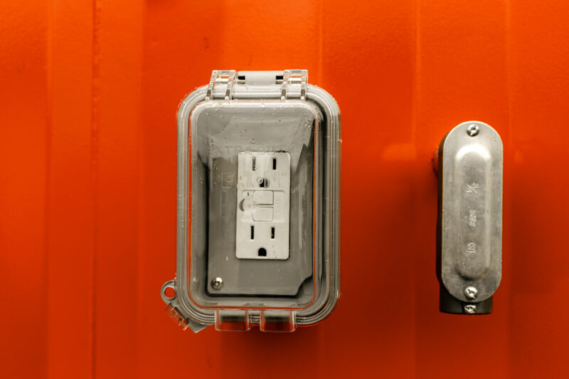 Weatherproof electrical outlet hardware on a jobsite restroom unit